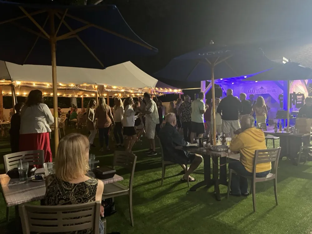 Diners on the lit-up patio at night under the tent